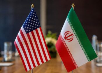 Sala diplomática vacía con banderas de Estados Unidos e Irán sobre una mesa de negociación. - Análisis de Tu Política